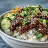 Sizzling Korean Ground Beef Bowl with seasoned meat over fluffy jasmine rice, topped with crisp pickled carrots, cucumbers, and radish for a savory, tangy bite.  
