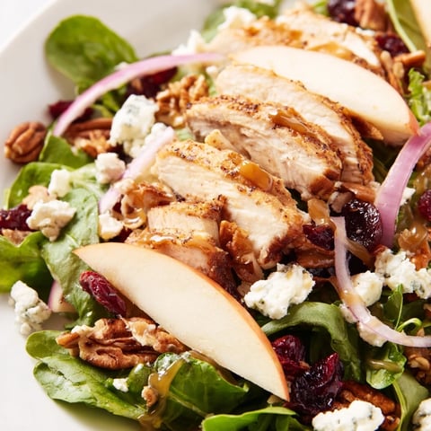 A vibrant Caramel Apple Chicken Salad with tender chicken, crisp apple slices, and candied pecans on mixed greens, drizzled with caramel dressing.