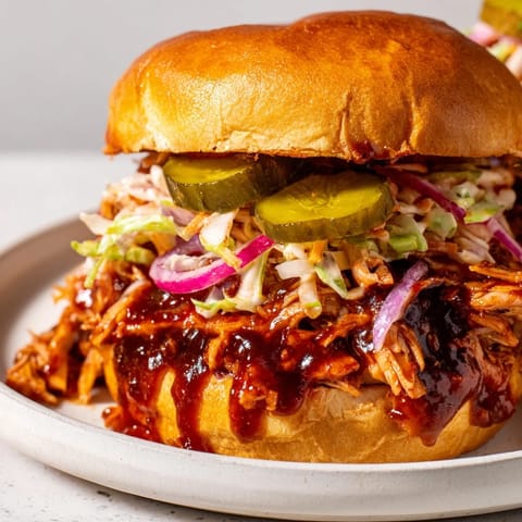 A close-up of a delicious BBQ chicken sandwich, with warm, savory chicken and a tangy sauce.
