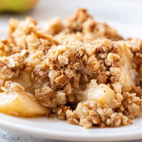 Freshly baked Apple Crumble, showcasing tender apples spiced with cinnamon and nutmeg; a cozy treat.