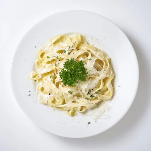 Al dente spaghetti coated in a velvety roasted garlic cream sauce, steaming gently beside a fork and glass of crisp white wine.