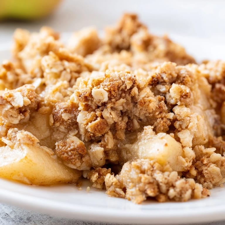 Freshly baked Apple Crumble, showcasing tender apples spiced with cinnamon and nutmeg; a cozy treat.