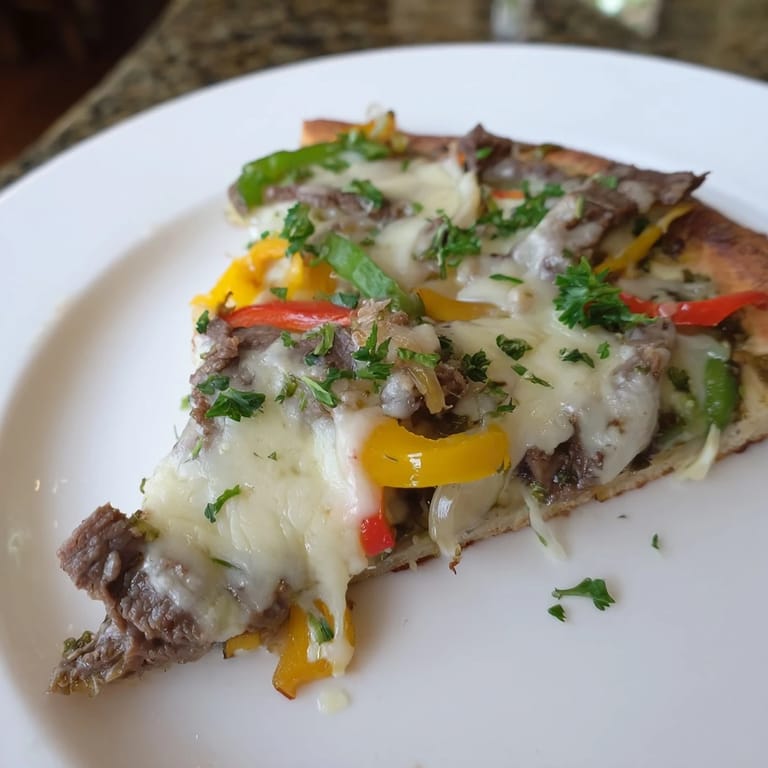 Enjoy the delicious layers of a cheesy Philly Cheesesteak Pizza, a quick and satisfying American classic.
