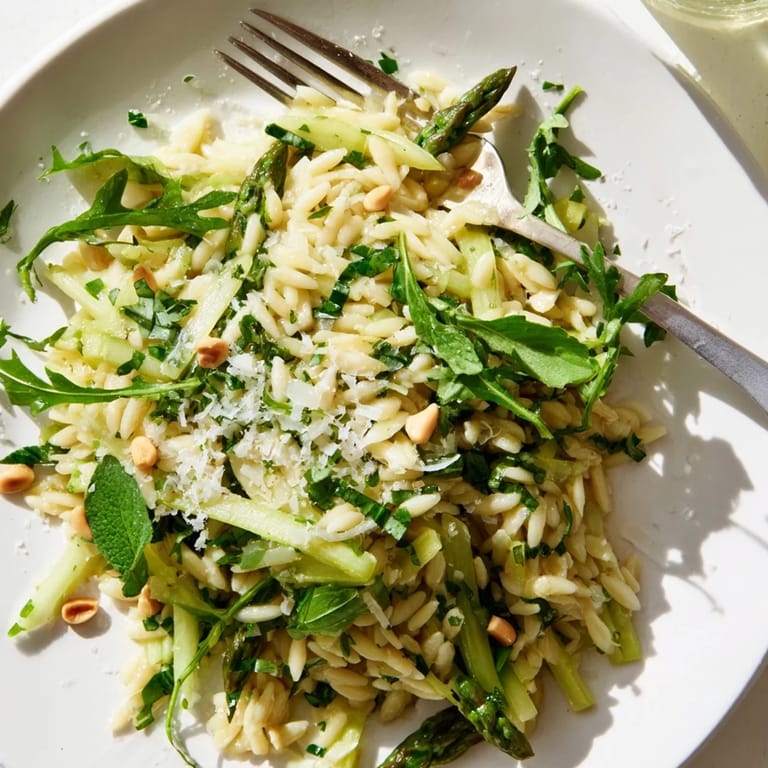Bright lemon dressing coats the fresh asparagus and orzo in this colorful Asparagus Lemon Orzo Salad, garnished with parsley and Parmesan.