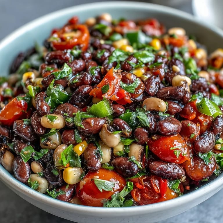 A close-up of freshly tossed Cowboy Caviar, highlighting juicy tomatoes and crisp vegetables coated in a zesty lime and cumin dressing.
