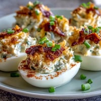 Spicy jalapeño popper deviled eggs with cream cheese, bacon, and cheddar make a bold appetizer.